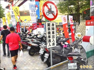 台南市立棒球場大門前人行道豎立嚴禁機車進入標誌，機車仍停放成排，民眾抱怨寸步難行。 （記者王俊忠攝）